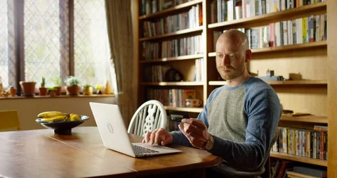 4k handsome young man using his laptop at home Stock Footage 128355482
