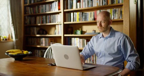 4k handsome young man using his laptop at home Stock Footage 128358967