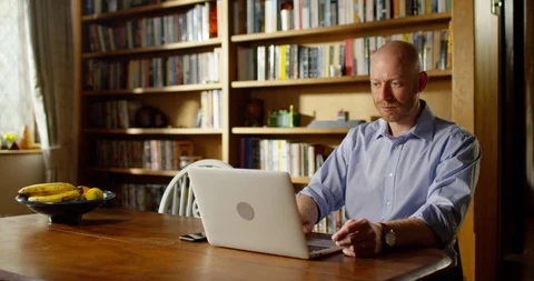 4k handsome young man using his laptop at home Stock Footage 128359382