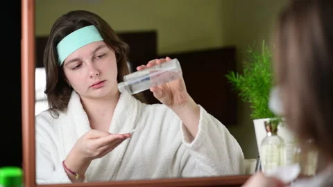 4k Happy attractive young woman applying a tonic at her pretty face Stock Footage