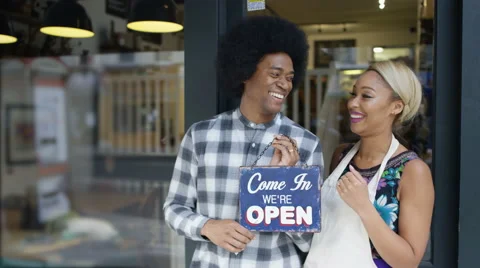 4K Happy cafe owner couple hold up a sign to show they are open for business. Stock Footage 64141553