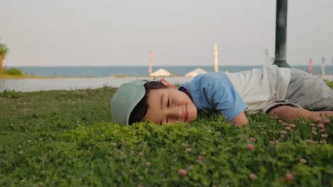 4k Happy child lay down on the grass and closes eyes Stock Footage 201113521