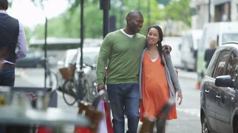 4K Happy couple expecting a baby walking with shopping bags in the city Stock Footage