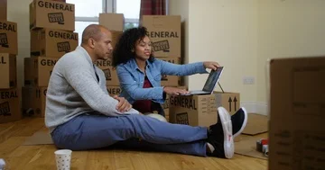 4K Happy couple looking at computer in new home, making decorating plans Stock Footage 85536254