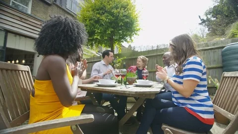 4K Happy friends enjoying lunch & drinks in the garden on a summer day Stock Footage