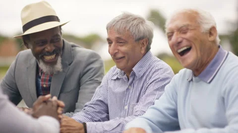 4K Happy senior male friends chatting & laughing together outdoors in the park Stock Footage