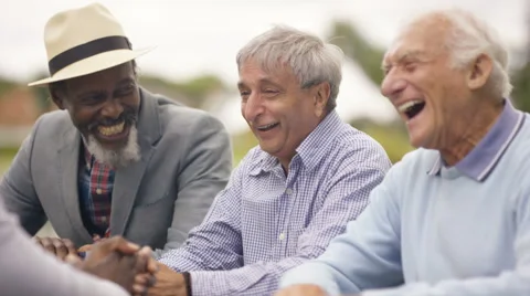 4K Happy senior male friends chatting & laughing together outdoors in the park Stock Footage