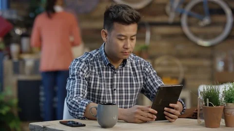 4K Happy young man looking at tablet &amp; drinking coffee in trendy cafe Stock Footage 76540173