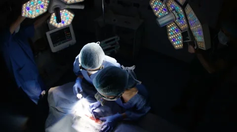 4K High angle view of team of surgeons operating on a patient in theater Stock Footage 63105809