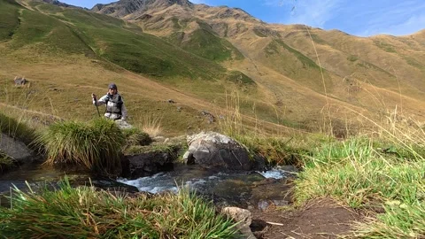 4K hiker crossing a mountain stream during a trekking adventure in Caucasus.. Stock-Footage 337444728