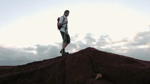4k Hiker with walking stick and red backpack in desert mountain terrain at sunse Vídeos de archivo 199619258