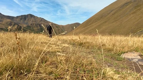 4K hiker walking through a mountain valley trail surrounded by golden grass.. Stock-Footage 337444743