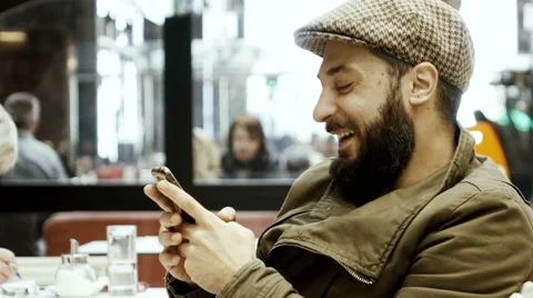 4k hip stylish man in cafe texts on smartphone laughs enjoys himself Stock Footage 61139917