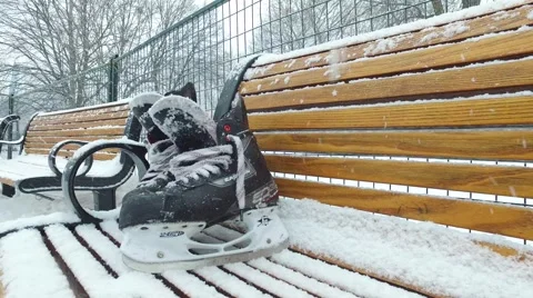 4k hockey skates sit on bench while it is snowing Stock Footage 61201853