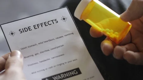 4K Holding Side Effects Paper and a Bottle Of Medication Pills Stock Footage