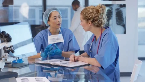 4K Hospital doctor prepared for surgery discussing patient notes with colleague. Stock Footage