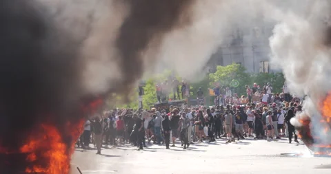 4K HUGE CROWD OF PROTESTORS BEHIND TWO HUGE PLUMES OF SMOKE Stock Footage 131453785