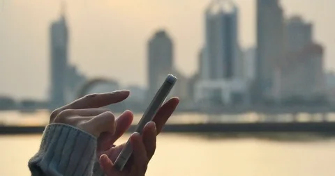 4k human using a smartphone aganist modern urban building skyline and coastline Vídeos de archivo 98779284