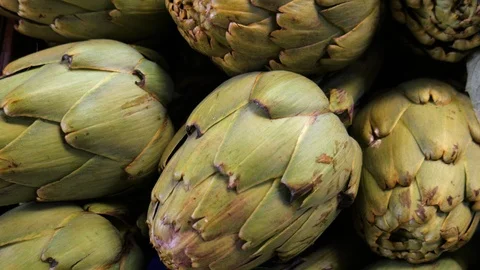 4k interior extreme close up pan shot of green fresh artichokes on a farmers Stock Footage 124275229