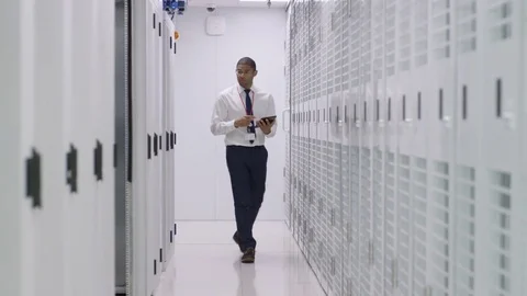 4K IT engineer checking servers in a data center with businessmen in background Stock Footage 75040348