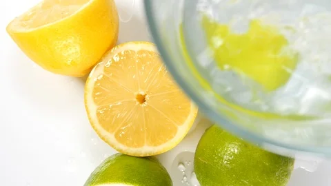 4k Lemons and limes dropping in glass of water, Bright yellow green citrus  Stock Footage 90191157