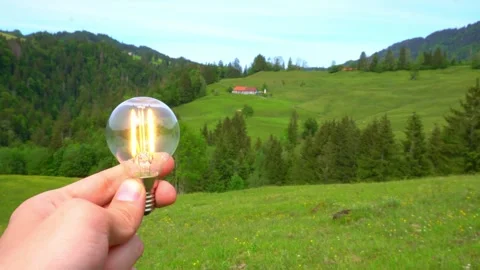 4k light bulb turns on main idea on a beautiful green landscape Stock Footage 276331602