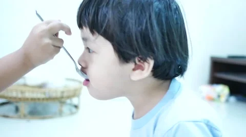 4K: little Asian boy eats rice soup for breakfast, video over light, 스톡 동영상 58012739