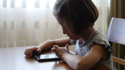 4k little girl in uniform using mobile phone iphone smart phone playing online Stock Footage 56581053