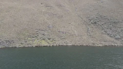 4K Log Drone Flying Backwards Revealing Lake and Hillside with hikers Ecuador Stock Footage 277211119