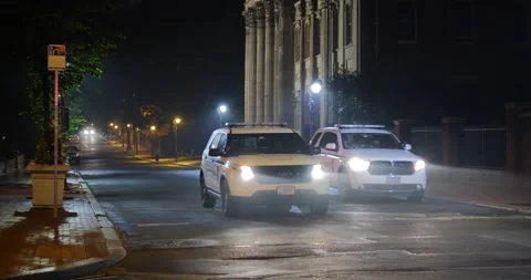 4K LONG SHOT EMPTY CITY STREET AT NIGHT WITH TWO COPS CARS Stock Footage 131108926