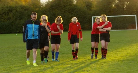 4K Losing girls' soccer team walking unhappily off pitch at the end of a game Stock Footage