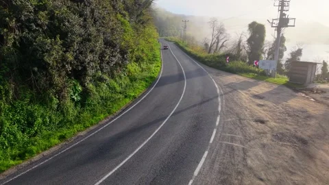 4K Low Drone Flight Along Foggy Road as a Classic Red Car Approaches from Behind Stock-Footage 339267544