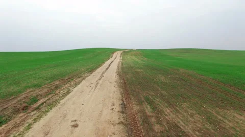 4K. Low flight above green fields with dirt road, aerial panoramic view. Vídeo Stock 55585746