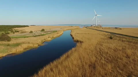 4K. Low flight over blue river and fields towards wind turbines and the sea. Stock-Footage 63136202