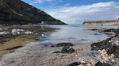 4K Low Shot of Calm Beach with Harbour Wall on a Sunny Day Stock Footage 276332113