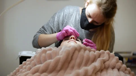 4K Makeup concept. The master of eyelash extension in pink gloves lengthens Stock Footage 105541353