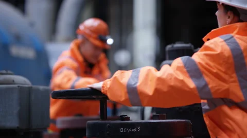4K Male & female engineers in power plant turning a valve on pipeline Stock Footage