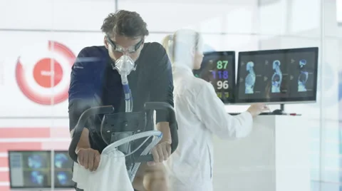 4K Man with breathing equipment on exercise bike having fitness levels analyzed Stock Footage 64893026