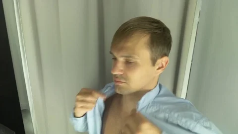 4k, A man chooses clothes for himself in a clothing store. Trying on new clothes Stock Footage 82912109