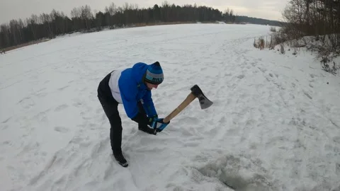 4K Man Chopping Ice With Axe In The Middle Of A Lake Making Ice Hole In Winter Stock Footage 157013057