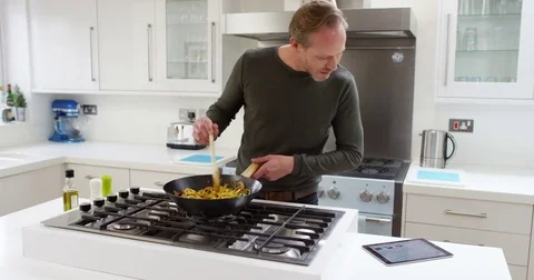 4K Man cooking alone at home, following a recipe on computer tablet Stock Footage 75279017