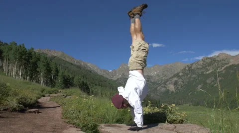 4k Man does handstand with scenic mountain back drop Video stock 56568549