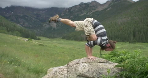 4k Man does yoga on rock in Colorado mountain valley Stock Footage 56568605