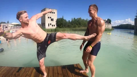 4K man kicks another man into water and then dives in Rummu Quarry as a joke Stock Footage 157013129