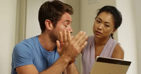 4K Man looking at computer worrying about bills &amp; his partner offering support Stock Footage 80470258