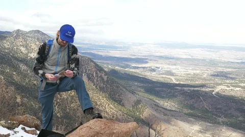 4K- Man Looking through Notepad On Top of Summit in Colorado Stock Footage 105356445