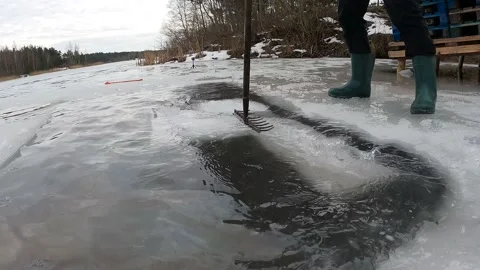 4K Man Making Ice Hole For Swimming With A Rake, Pushing Down Ice In Winter Stock Footage 157013137