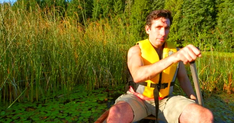 4K Man Paddling Canoe through Reeds on Lake Stock Footage 41724538