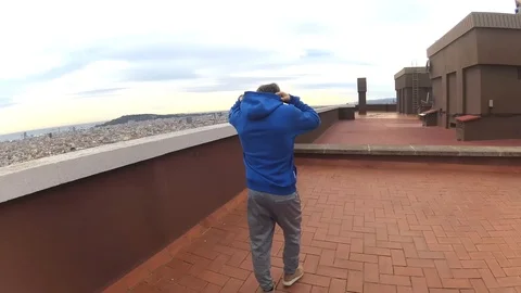 4k Man performs stretching on top of a rooftop with a view Stock Footage 120697540