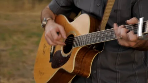 4k of Man playing the guitar in mountain field Stock Footage 105086587